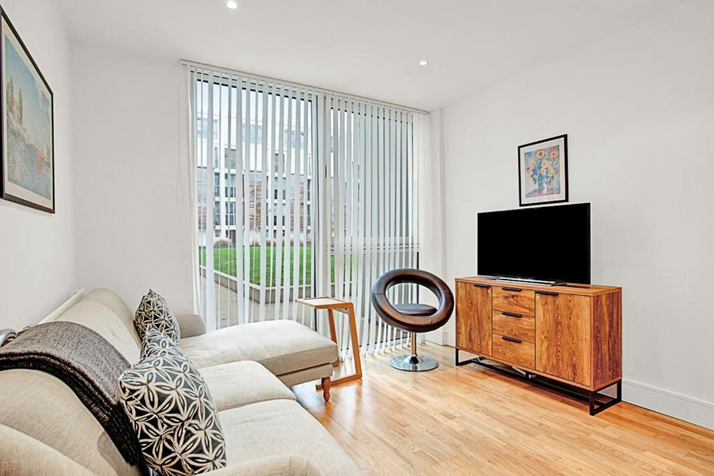 a living room with a couch and a flat screen tv at Urban Retreat Stylish 1-Bed Bliss in London