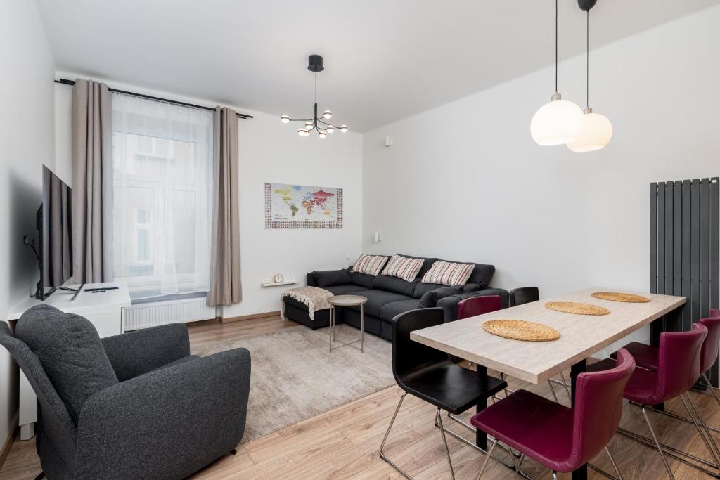Vistula River 2-Bedroom Apartment في كراكوف: غرفة معيشة مع طاولة وأريكة