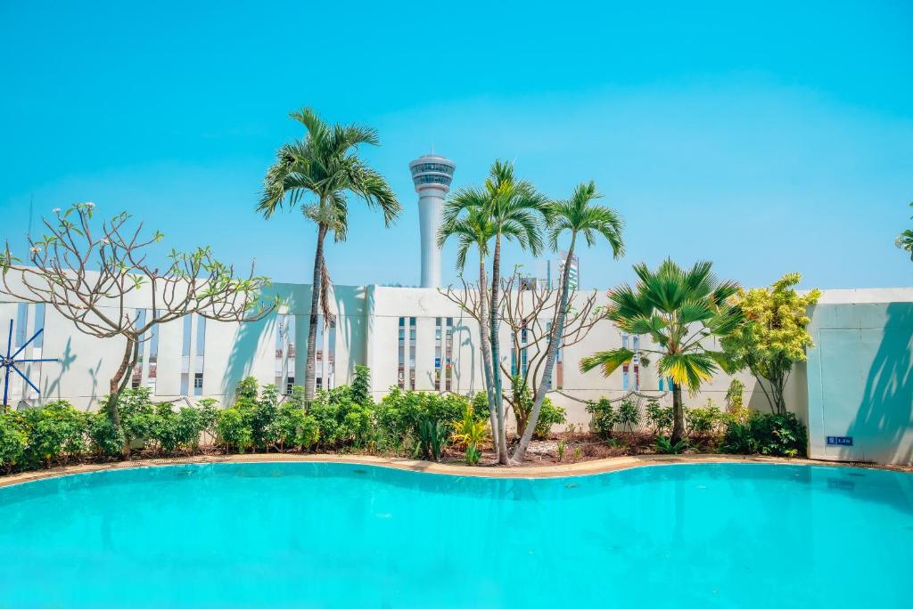 呵叻的住宿－Fortune Hotel Korat- SHA Plus，棕榈树建筑前的游泳池