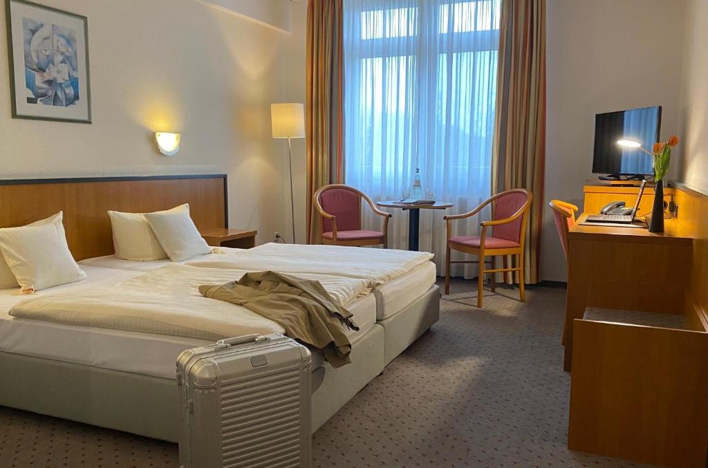 pokój hotelowy z łóżkiem i walizką w obiekcie Andersen Hotel Birkenwerder w mieście Birkenwerder