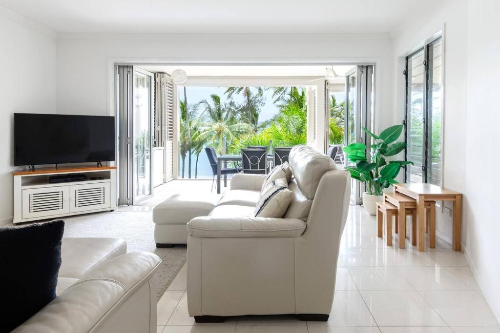 ein Wohnzimmer mit weißen Möbeln und einem TV in der Unterkunft Rojo at Island Views—A Breezy Beachfront Retreat in Palm Cove