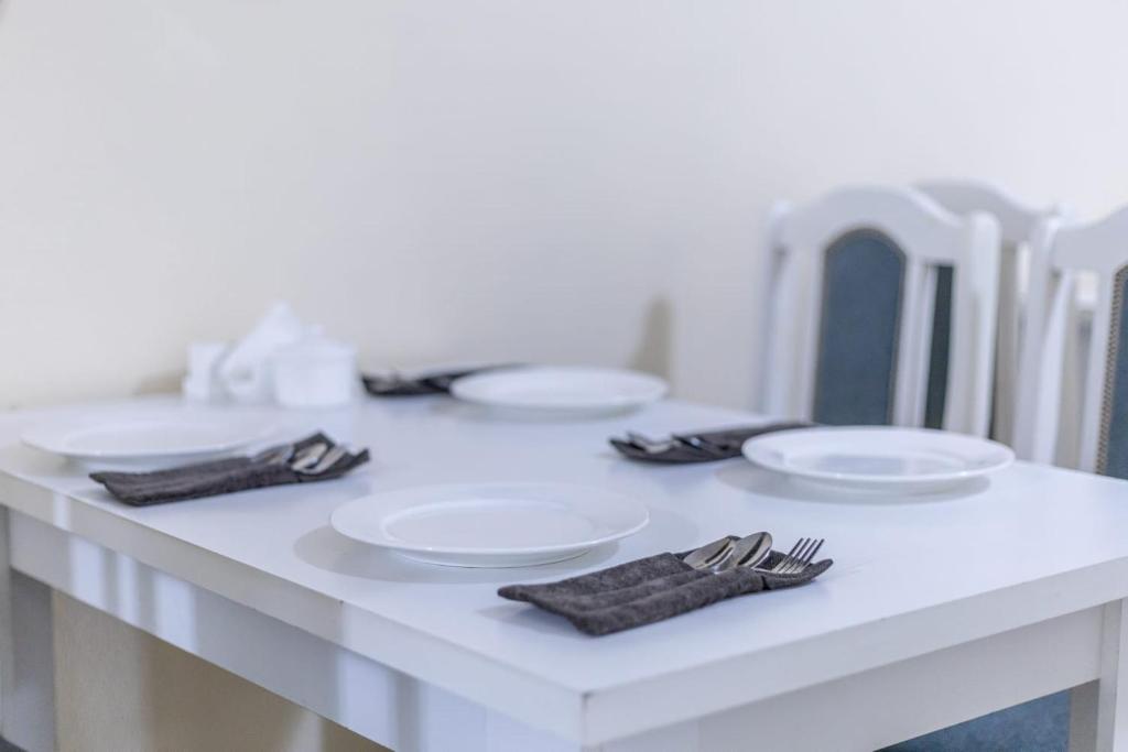 a white table with plates and silverware on it at Алматы Транзит №1 in Turksib