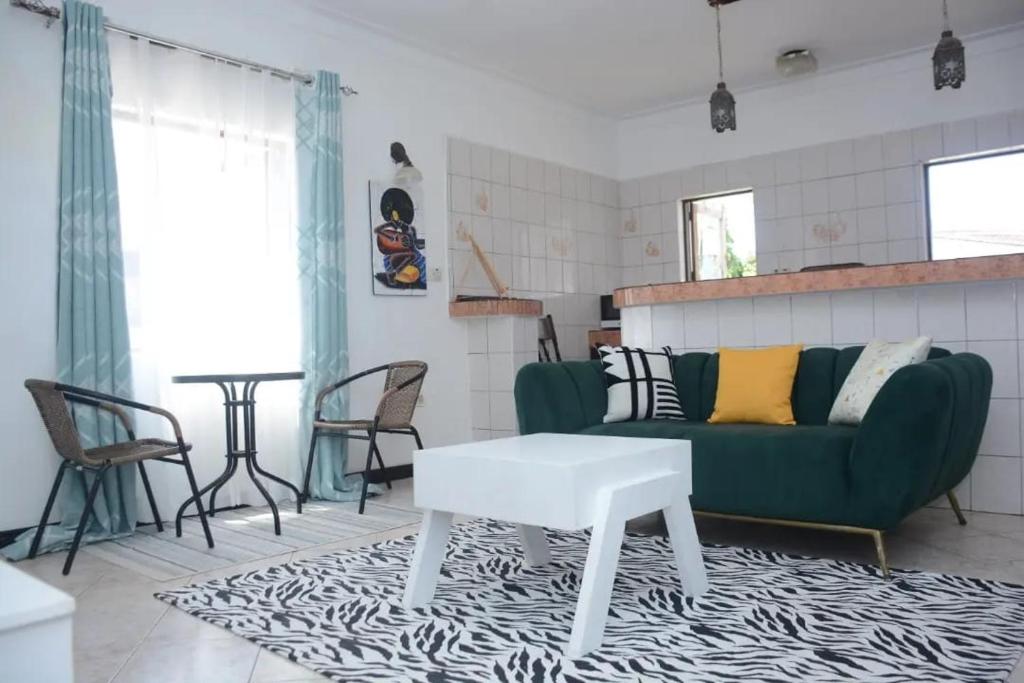 ein Wohnzimmer mit einem grünen Sofa und einem Tisch in der Unterkunft Carel Holiday Homes in Mombasa
