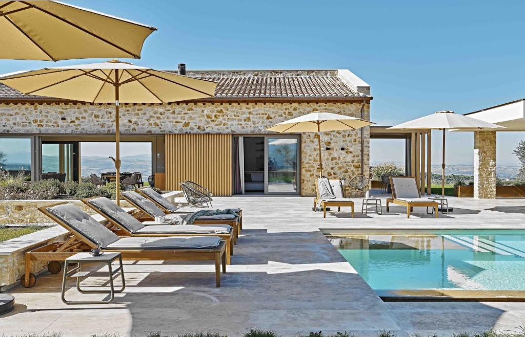 - un groupe de chaises longues et de parasols à côté de la piscine dans l'établissement Scappo in Umbria, Il Momento, à Todi