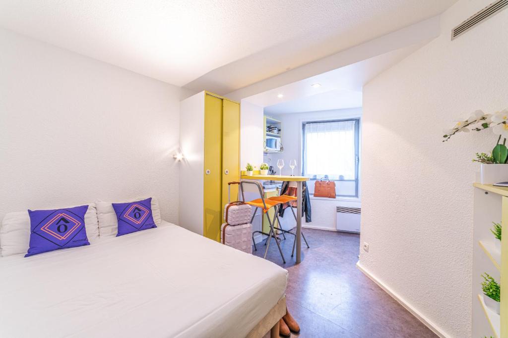 um pequeno quarto com uma cama e uma mesa em Montempô Apparthôtel Evry em Courcouronnes
