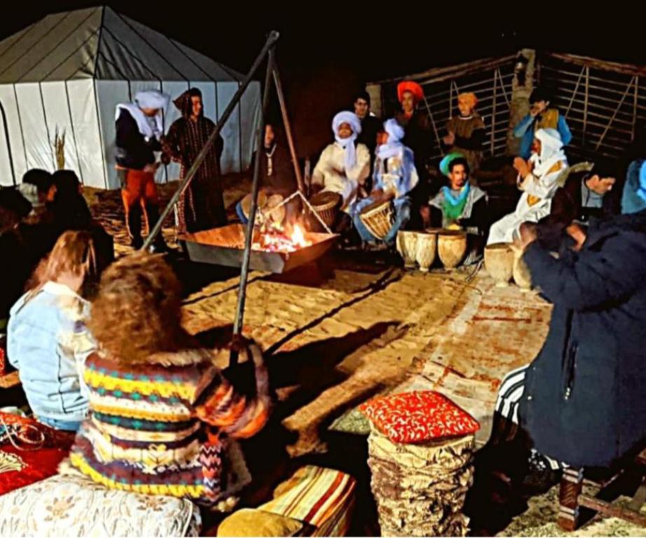 a group of people sitting around a fire at Comfort Luxury Camp in Merzouga
