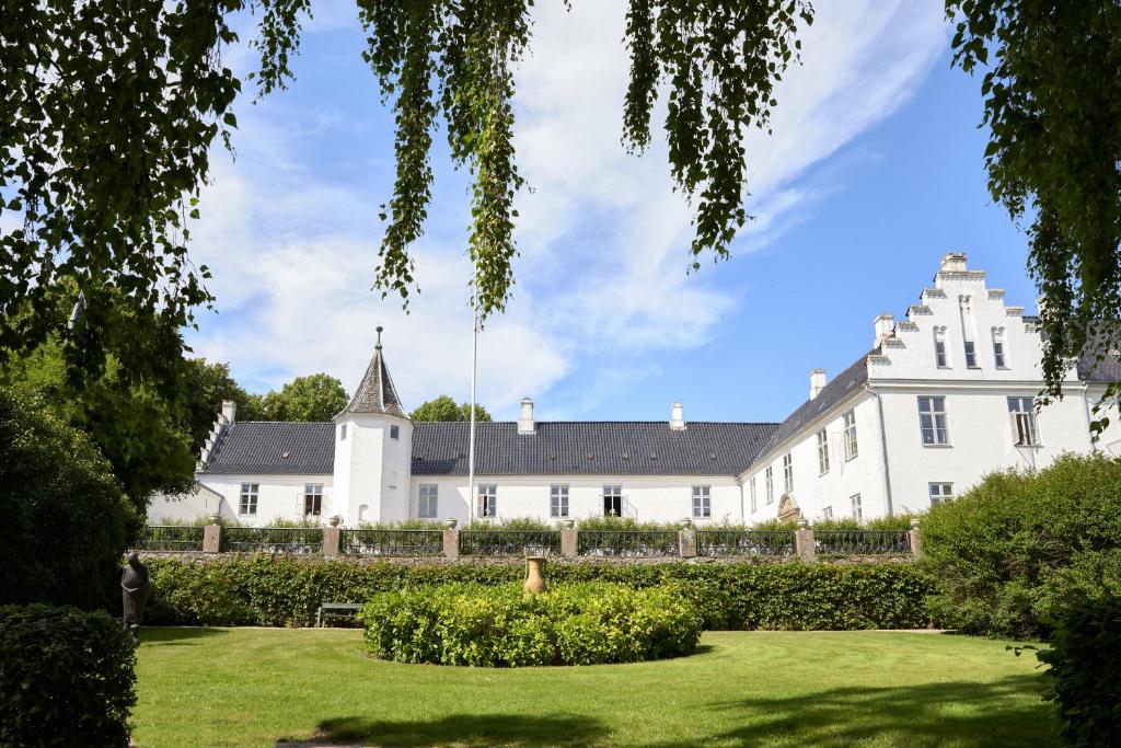 una gran casa blanca con césped delante en Dallund Slot, en Søndersø