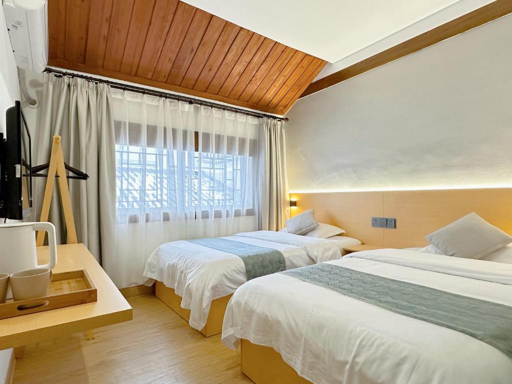 a hotel room with two beds and a window at Hemu House in Fenghuang County