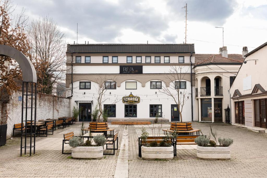 a building with tables and benches in a courtyard at RIVA sleep & chill in Valjevo