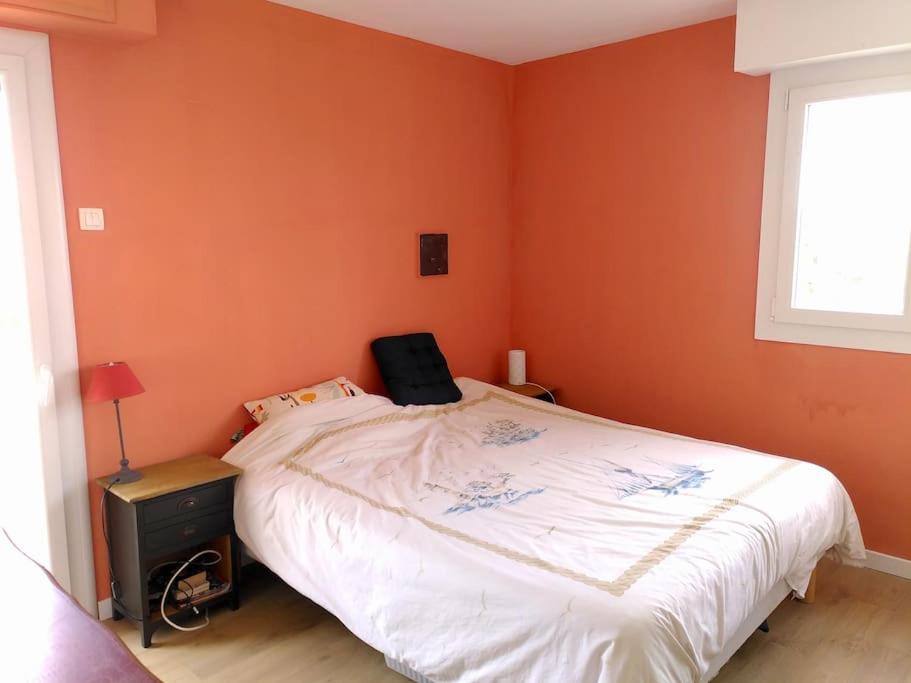 a bedroom with a large bed with orange walls at Appart T3 Spacieux + Terrasse in Montpellier