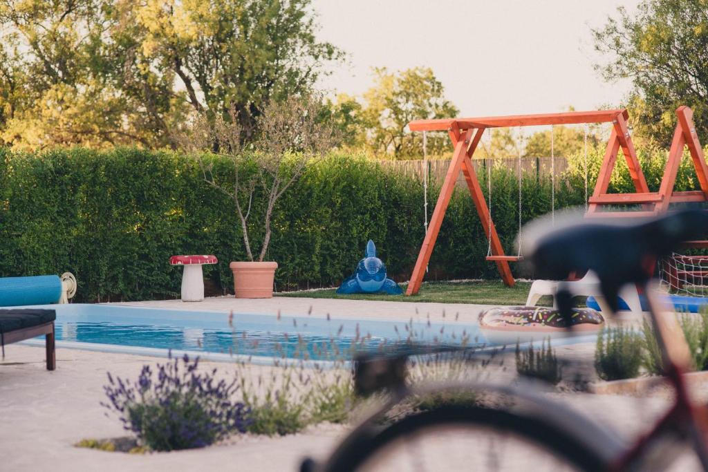 een speeltuin met een zwembad en een schommel bij Cozy country home with heated outdoor pool in Šibenik