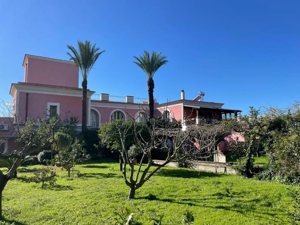 una casa rosa con palmeras delante en Villa Aura, en Torre del Greco