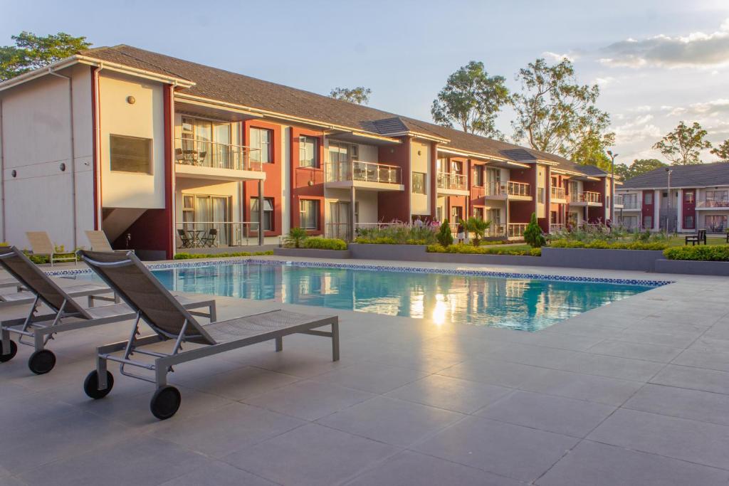 a villa with a swimming pool and two lounge chairs at Cherrywood Estate Apartment in Blantyre