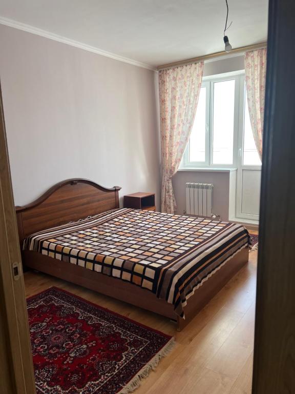a bedroom with a bed in a room with a window at 2 комнатная квартира in Taldykolʼ