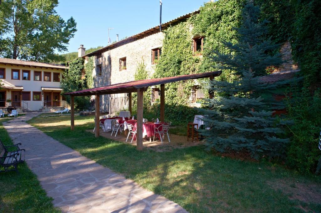 - un jardin avec une table et des chaises en face d'un bâtiment dans l'établissement Hotel Charle, à Jaca