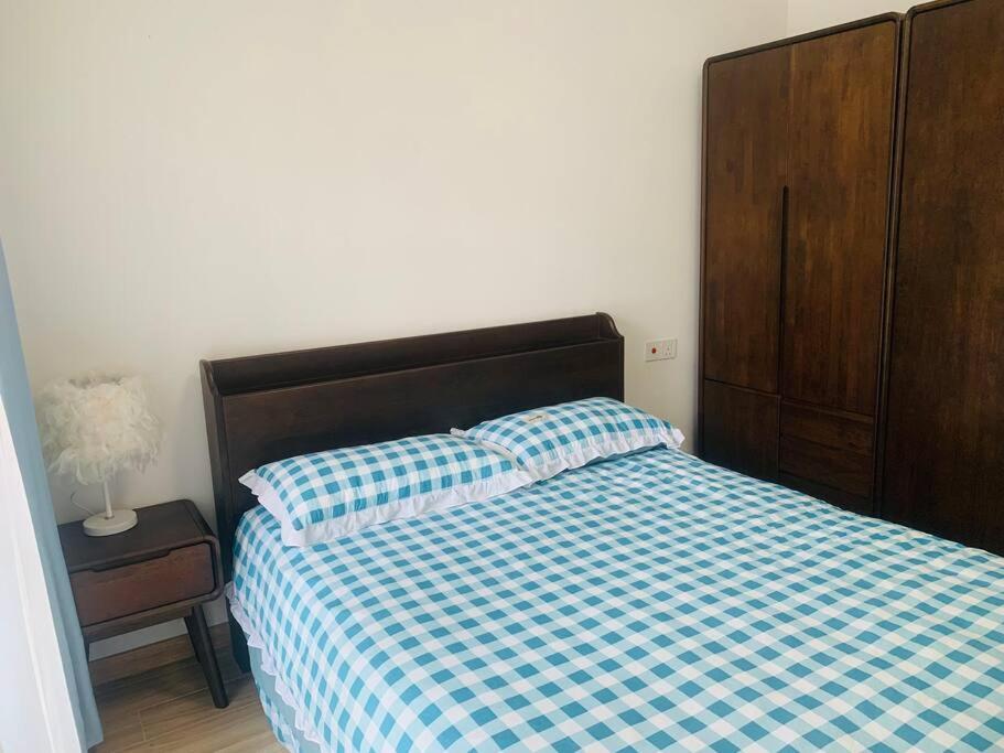 温馨别致1+2房 في Kampong Pok Kechil: غرفة نوم بسرير من اللون الأزرق والأبيض وتفقد الشراشف