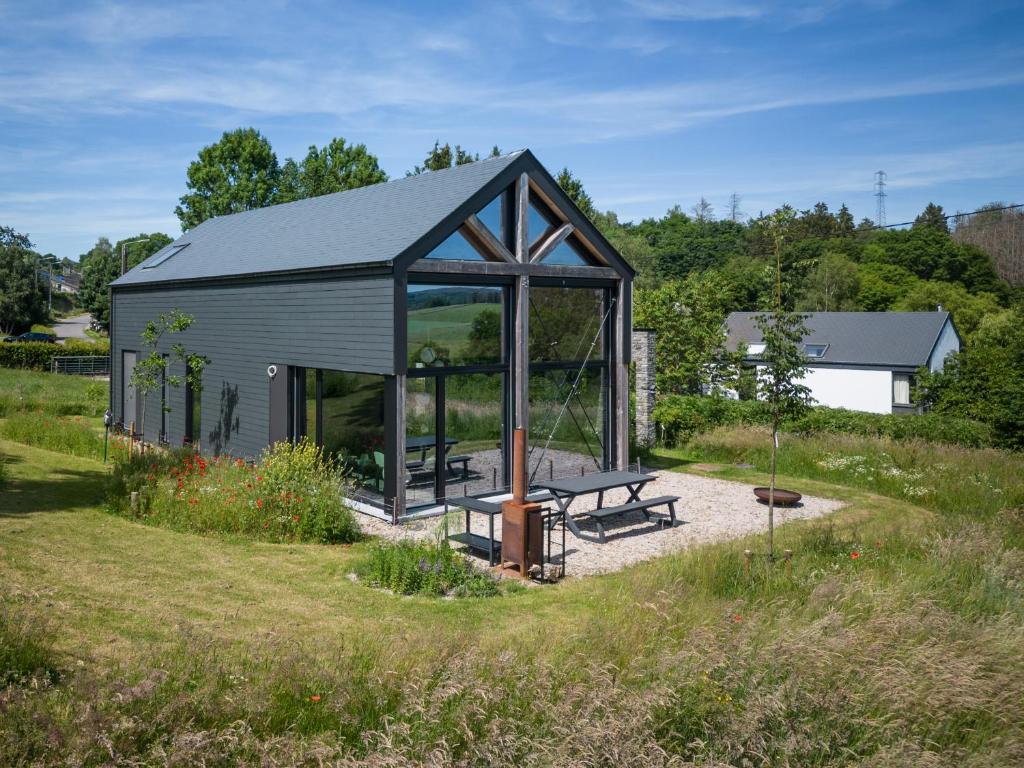 a shed with a picnic table in the middle of a field at Arduenna Silva ecologic designer house in La-Roche-en-Ardenne