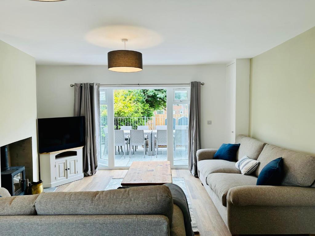 uma sala de estar com dois sofás e uma televisão em Coastal Cottage with hot tub, sleeps 10 em Bacton