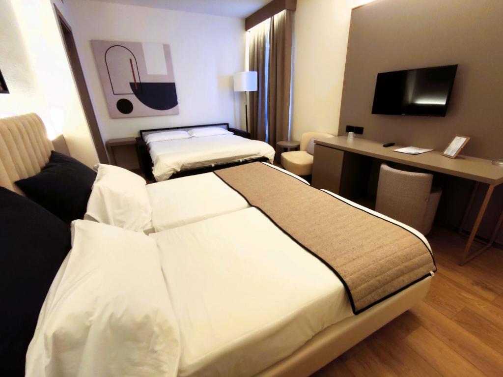 a hotel room with two beds and a desk at Vittoria Parc Hotel in Bari