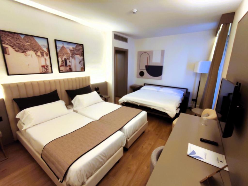 a hotel room with two beds and a desk at Vittoria Parc Hotel in Bari