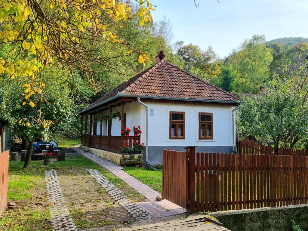 una pequeña casa en un patio con una valla en Hutai Meseház en Háromhuta