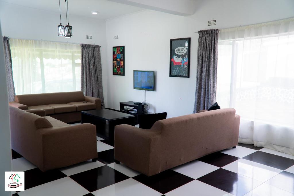 a living room with two couches and a checkered floor at Likulezi Apartment 1 in Blantyre