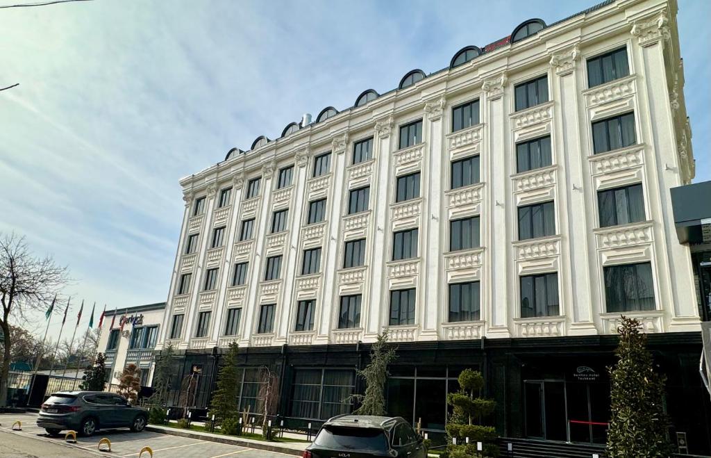 a large white building with cars parked in front of it at Bentley Hotel Tashkent in Tashkent