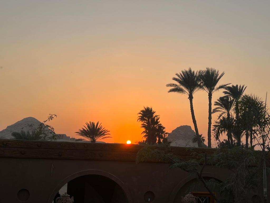 a sunset with palm trees and a bridge at peace house in Cairo