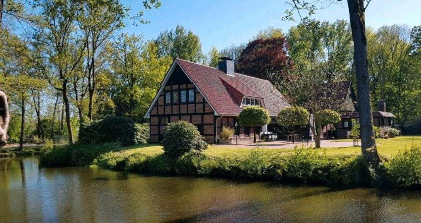 a house sitting next to a river with a house at Gut Stedingsmühlen in Molbergen