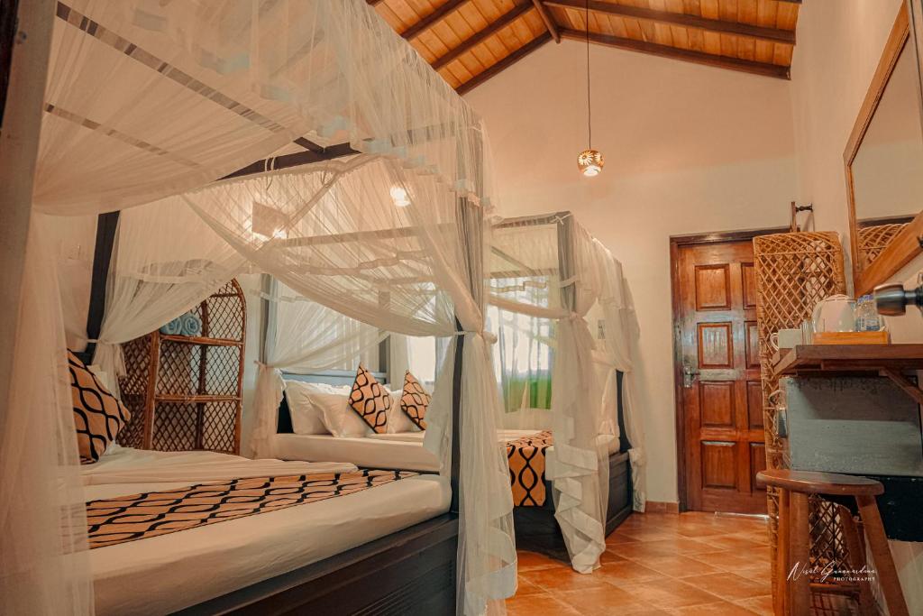 een slaapkamer met twee stapelbedden met klamboes bij MANTA RAY MANOR HAVEN -Nestled on Sri Lanka's Southern Coast, offers Luxurious rooms with Ocean, Garden, & Pool Views, a Private Beach, Ocean-View Pool with a Jacuzzi, & Event Hosting & more, your Perfect Escape for Relaxation & Unforgettable Moments in Ahangama