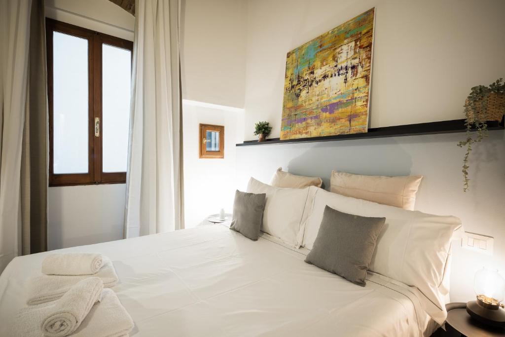 uma cama com lençóis brancos e almofadas num quarto em Agnolo Boutique Apartment - central Florence accomodation em Florença