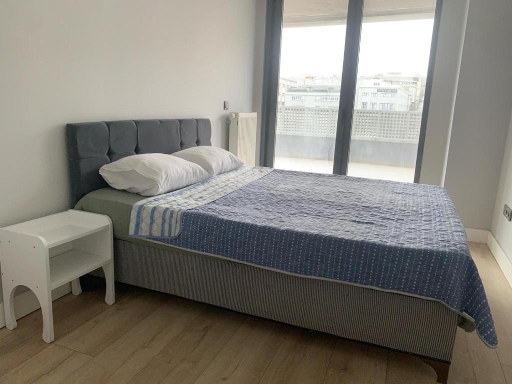 a bedroom with a bed with a blue comforter and a window at Fantastic apartment two rooms in Istanbul