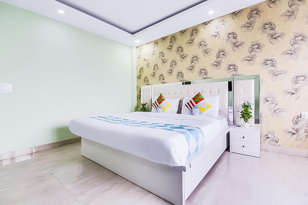 a white bedroom with a large white bed and wallpaper at Hotel Satguru - Dwarka Mor Metro in New Delhi