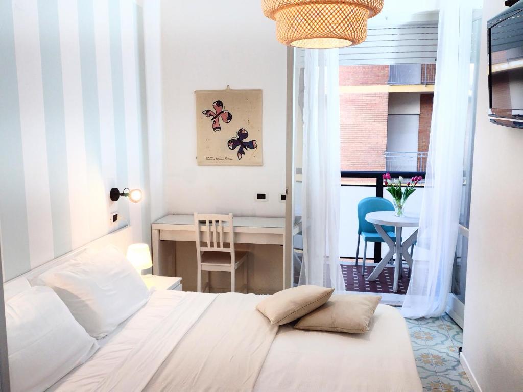 1 dormitorio con cama blanca, escritorio y mesa en Hotel Ambasciata, en Cesenatico