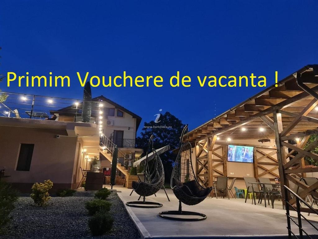 a house with two chairs in a courtyard at night at Pensiunea Lotus Corbu in Corbu