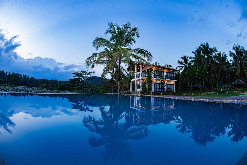 a house with a palm tree next to a body of water at Village Paradise in Beliatta