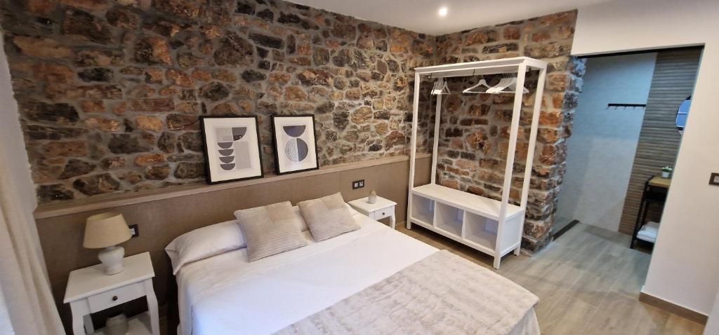 a bedroom with a bed and a stone wall at Apartamentos Entrellusa in Perlora