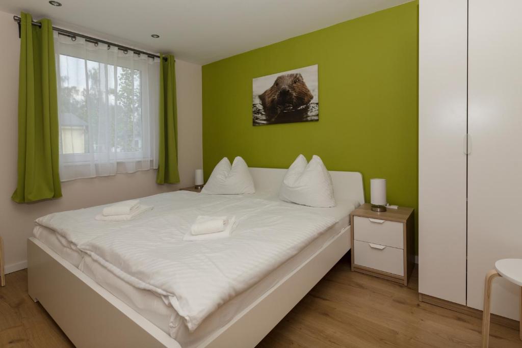een slaapkamer met een wit bed en een groene muur bij Ferienhaus Biber im Sternenpark in Lochow