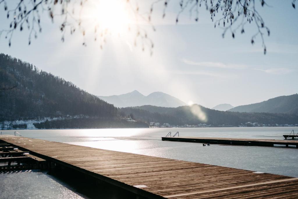 a dock on a lake with mountains in the background at Hotel Greif in Sankt Kanzian