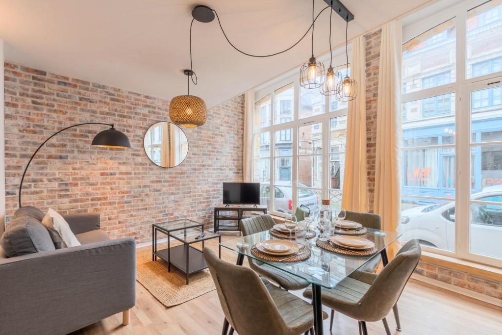 een woonkamer met een bakstenen muur en een tafel en stoelen bij Unique apartment in the Old Lille ! in Lille