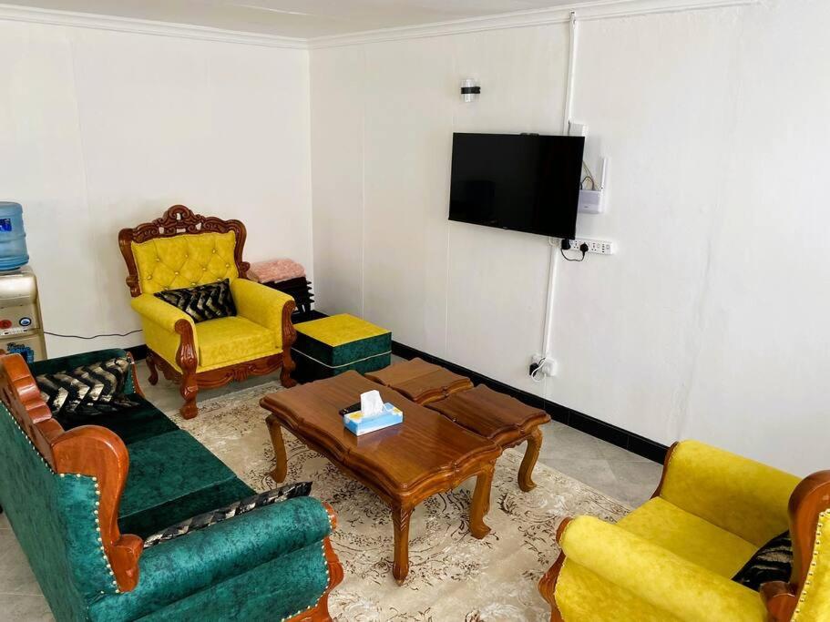 een woonkamer met gele en groene stoelen en een tv bij 3 Bedroom Laneens Nest in Nakuru