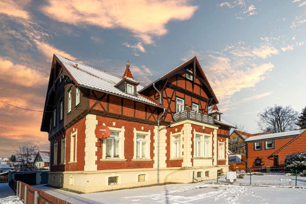 une grande maison en bois avec de la neige au sol dans l'établissement Wanderlust Wernigerode - Dein Tor zum Harzer Abenteuer, à Wernigerode