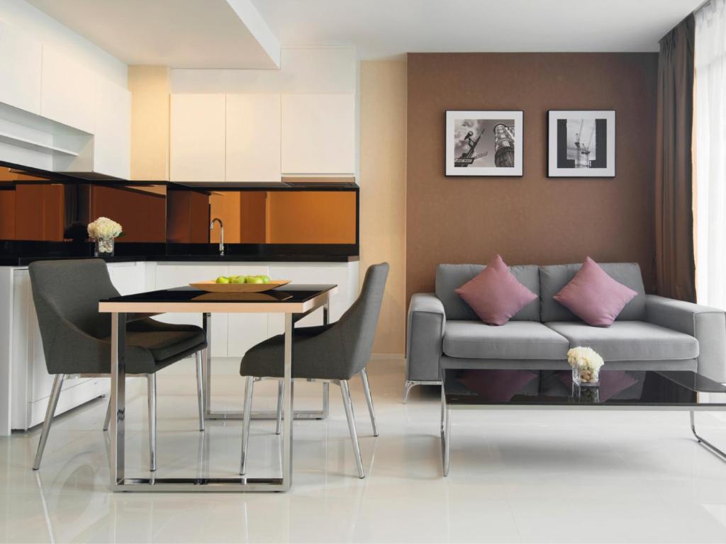 a living room and kitchen with a couch and a table at Mövenpick Residences Ekkamai Bangkok in Bangkok