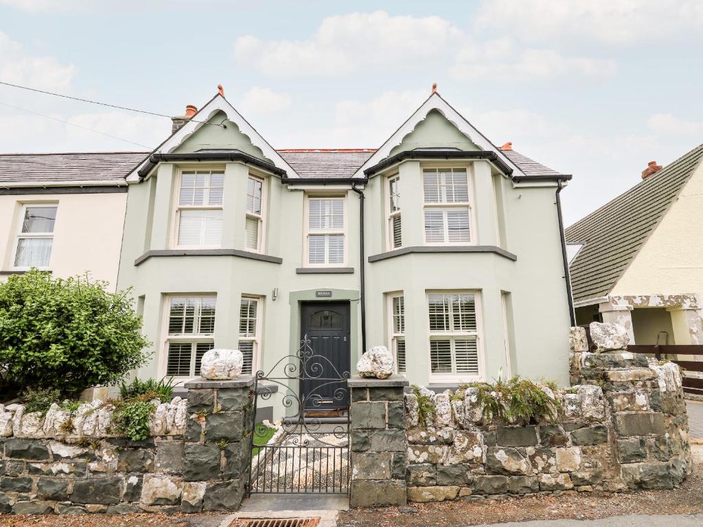 a white house with a stone fence at Dolwern in Newport