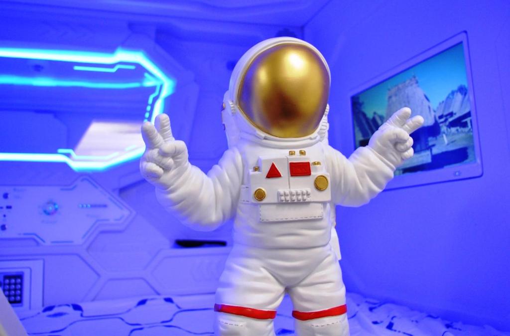 a man in an astronaut suit holding up his hands at Cosmos capsule coworking London in London