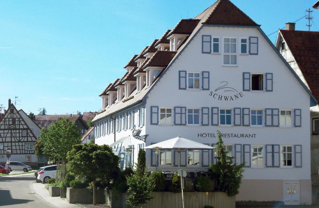 un gran edificio blanco con un cartel. en Hotel Garni Schwane en Meßstetten