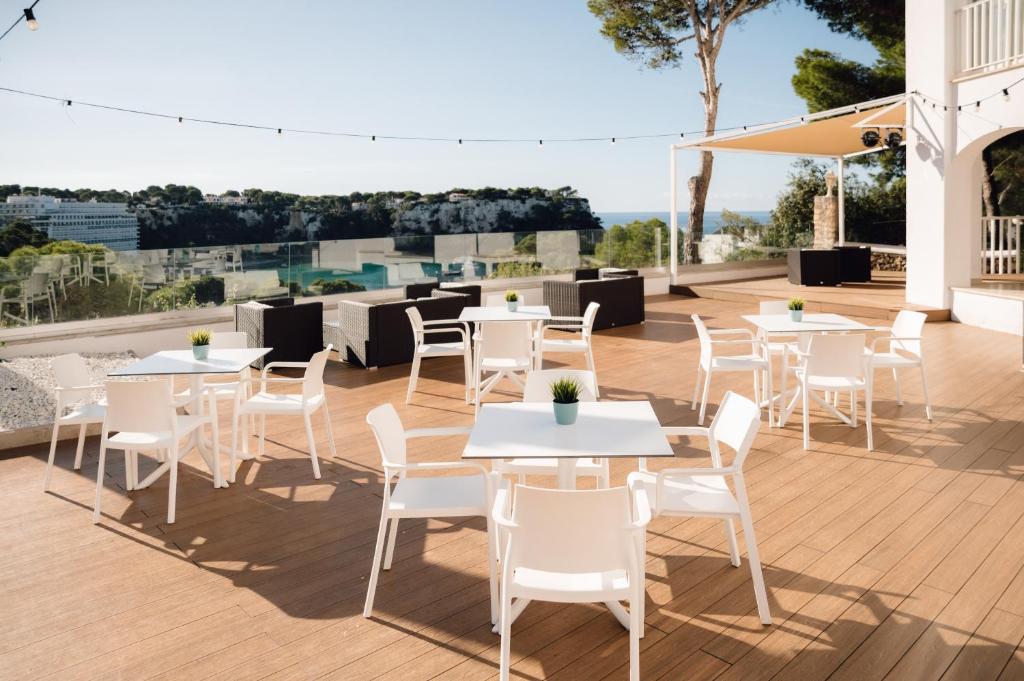 a patio with white tables and chairs on a deck at Comitas Floramar in Cala Galdana