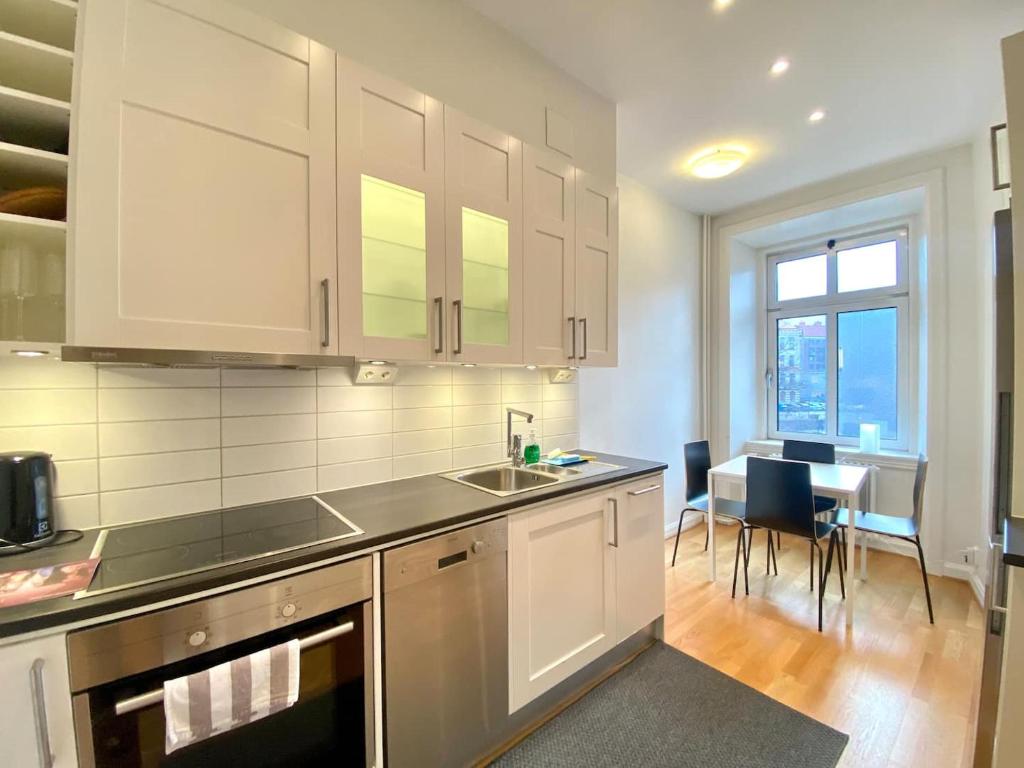 a kitchen with white cabinets and a sink and a table at Luxury Apartment In City Centre in Gothenburg