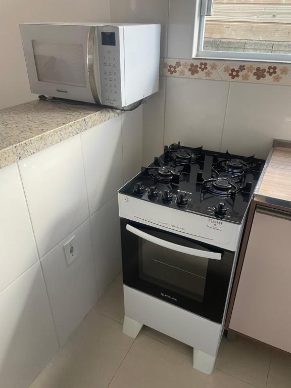 a kitchen with a stove and a microwave at Praia dos ingleses Floripa in Florianópolis
