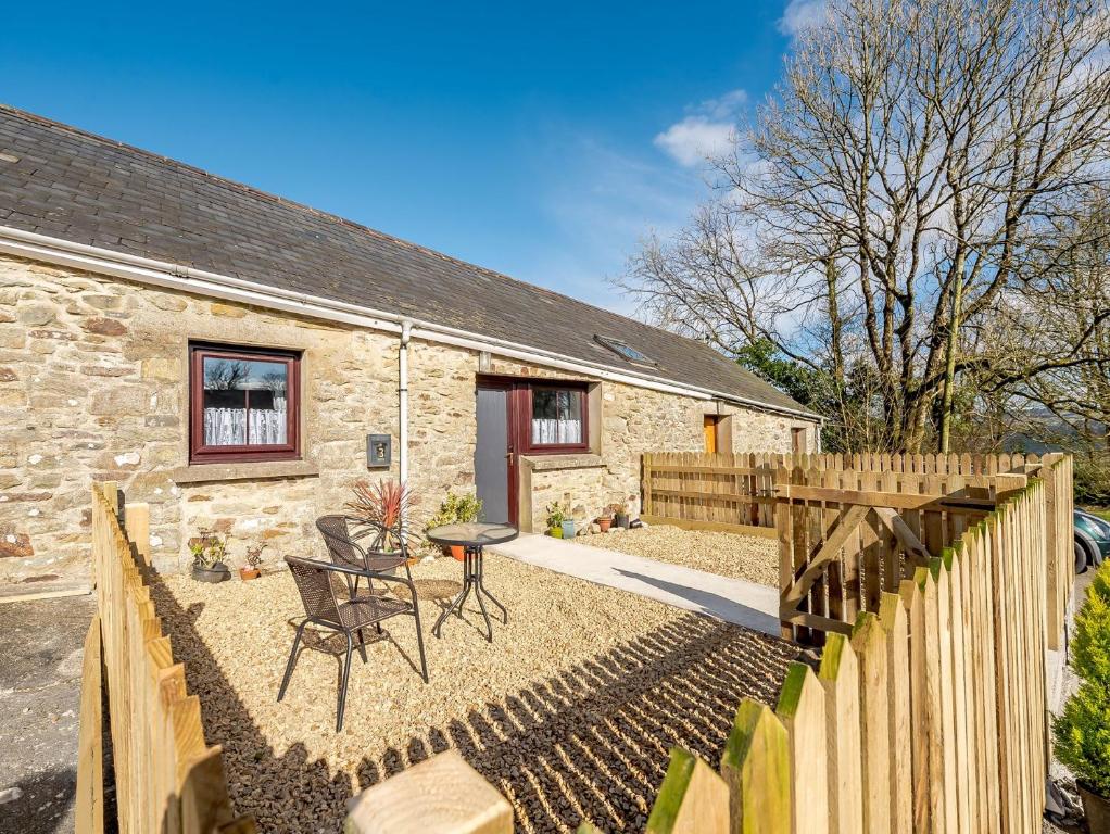 a stone cottage with a fence and a table and chairs at 1 bed in Brynteg 87362 in Llanwenog